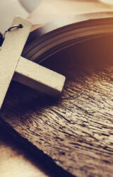 Closeup of simple wooden Christian cross necklace on Bible vintage tone god