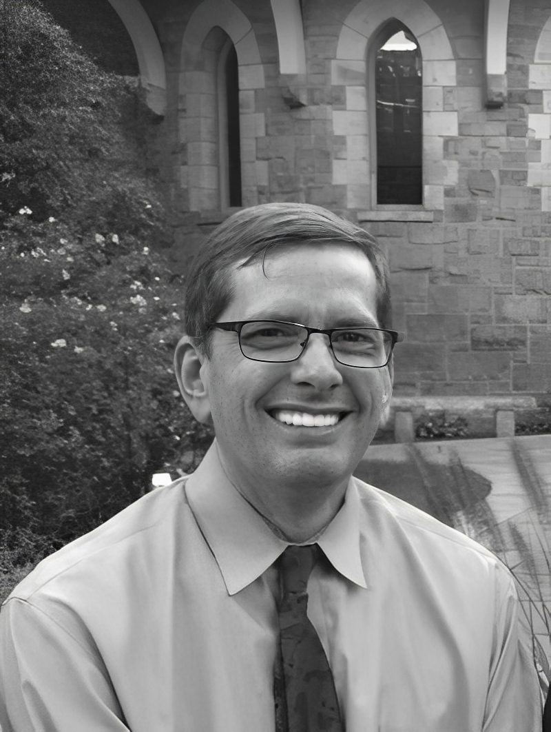 Smiling man wearing glasses and tie outdoors