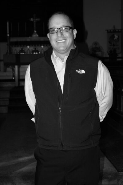 Individual standing indoors with a smile