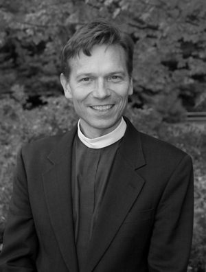 Smiling man in clerical attire outdoors