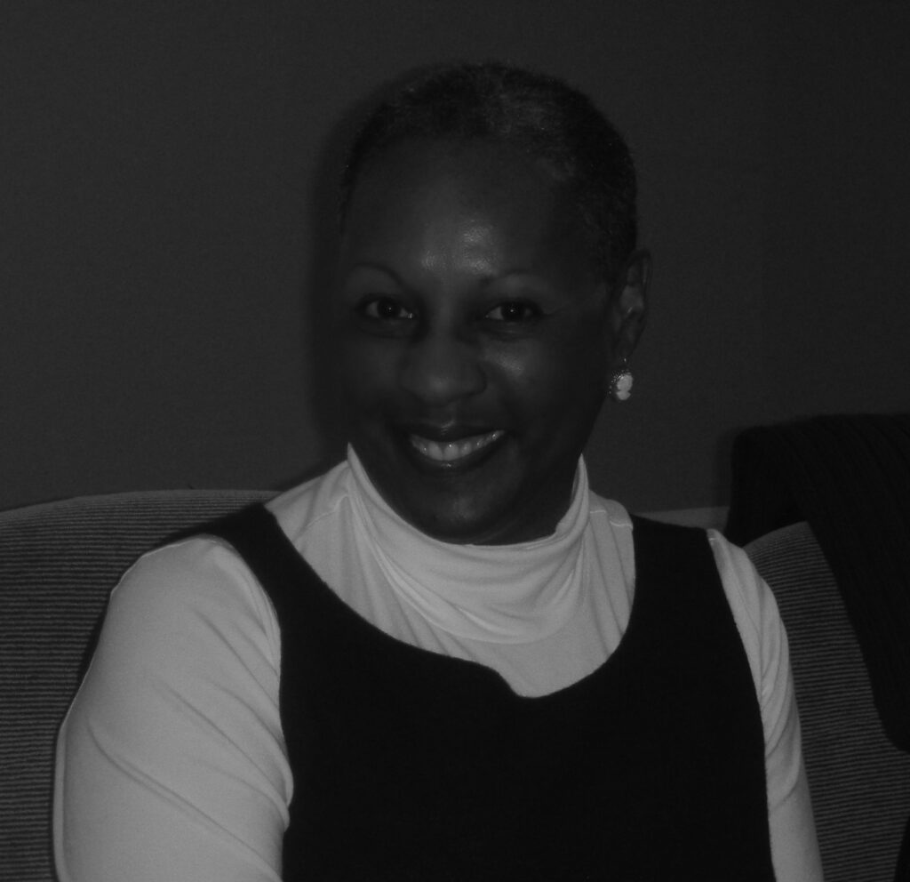 Woman sitting wearing a dark top and earrings