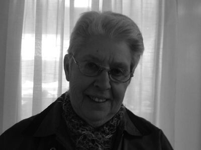 Elderly person smiling in front of curtains