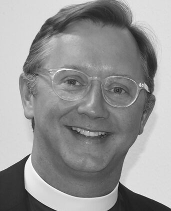 Man wearing clerical collar and glasses