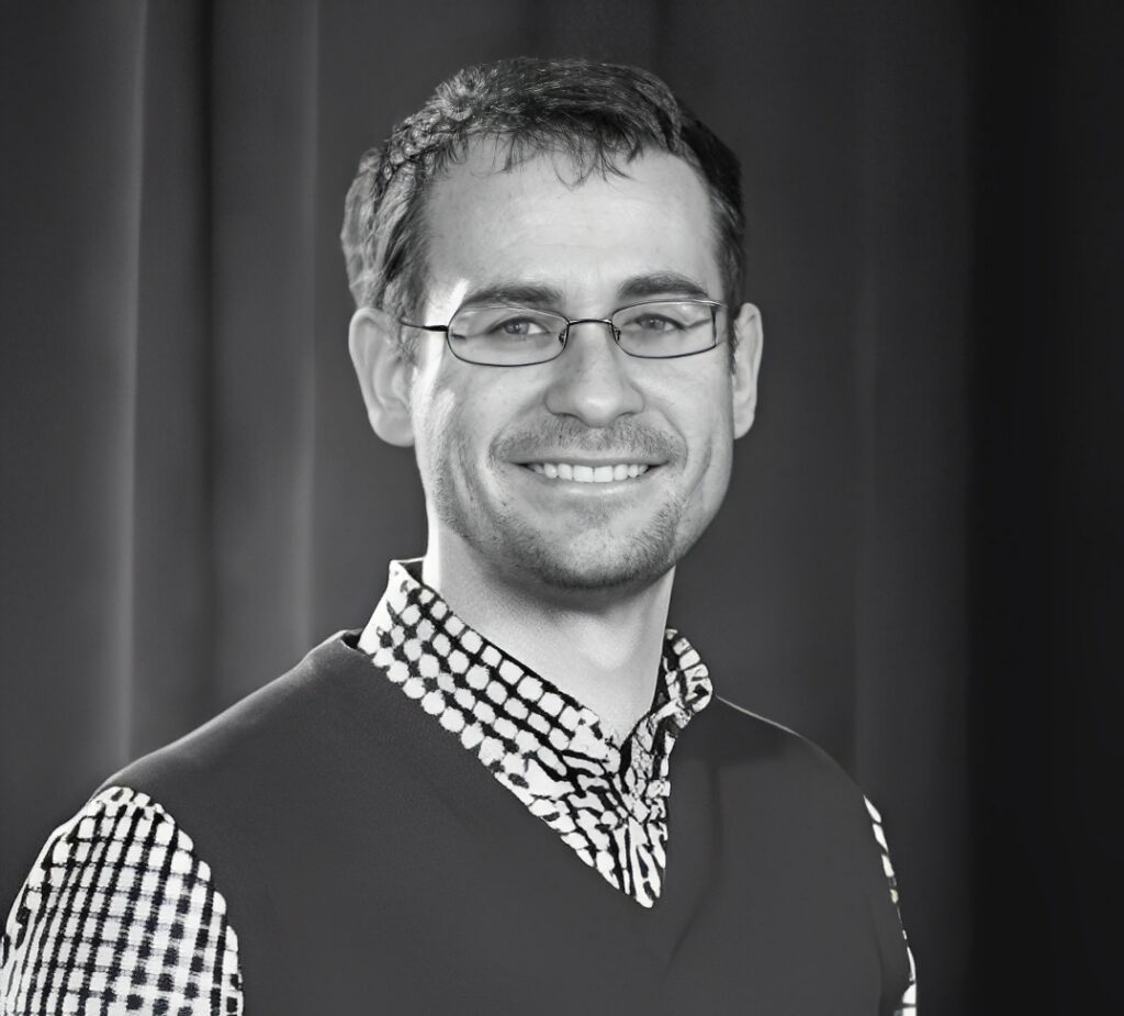 Smiling man wearing glasses and patterned shirt