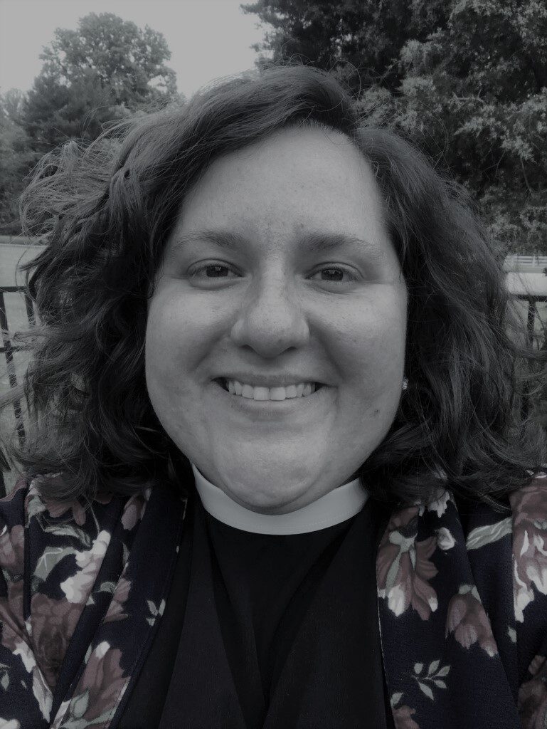 Smiling person outdoors with trees behind