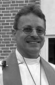 Priest standing outdoors, smiling