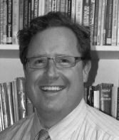Smiling man in front of bookshelves