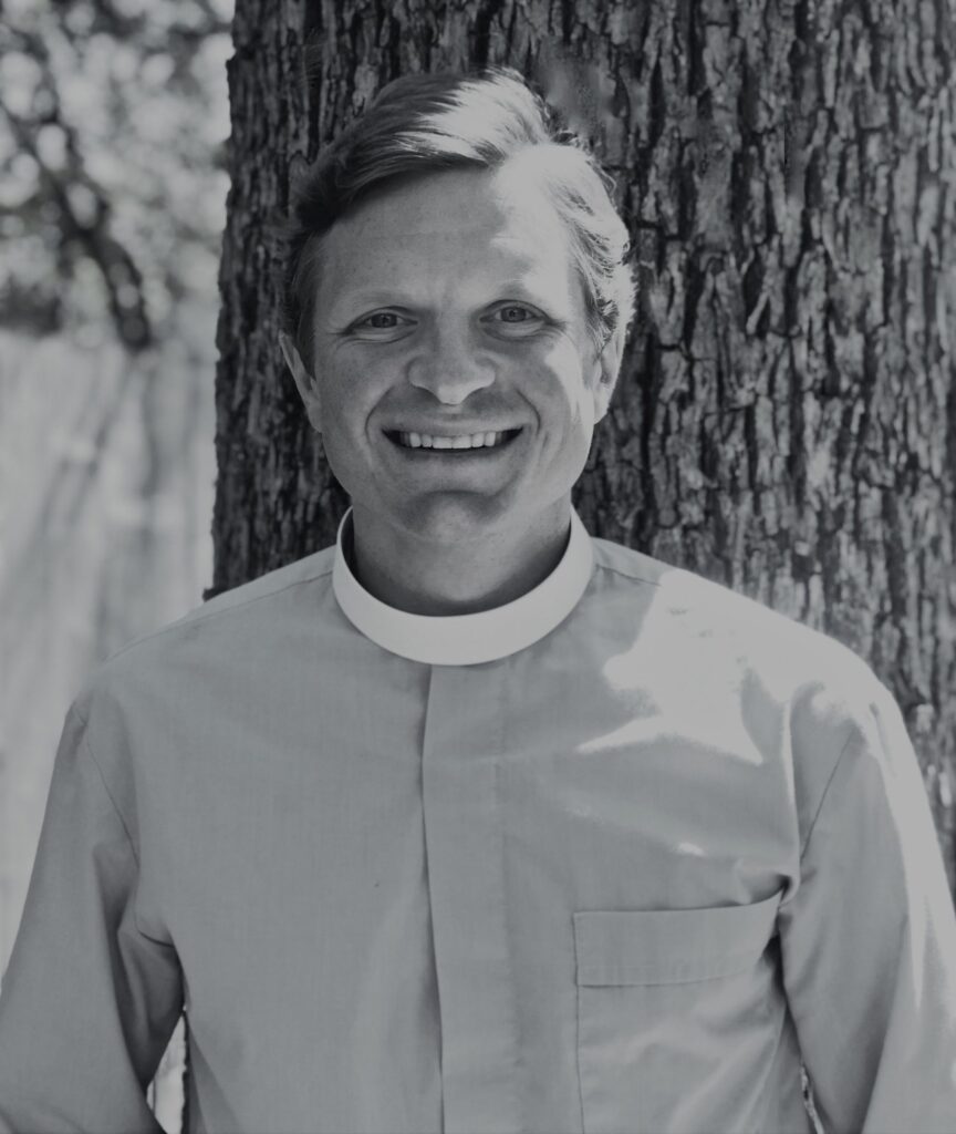 Smiling person in clerical attire outdoors