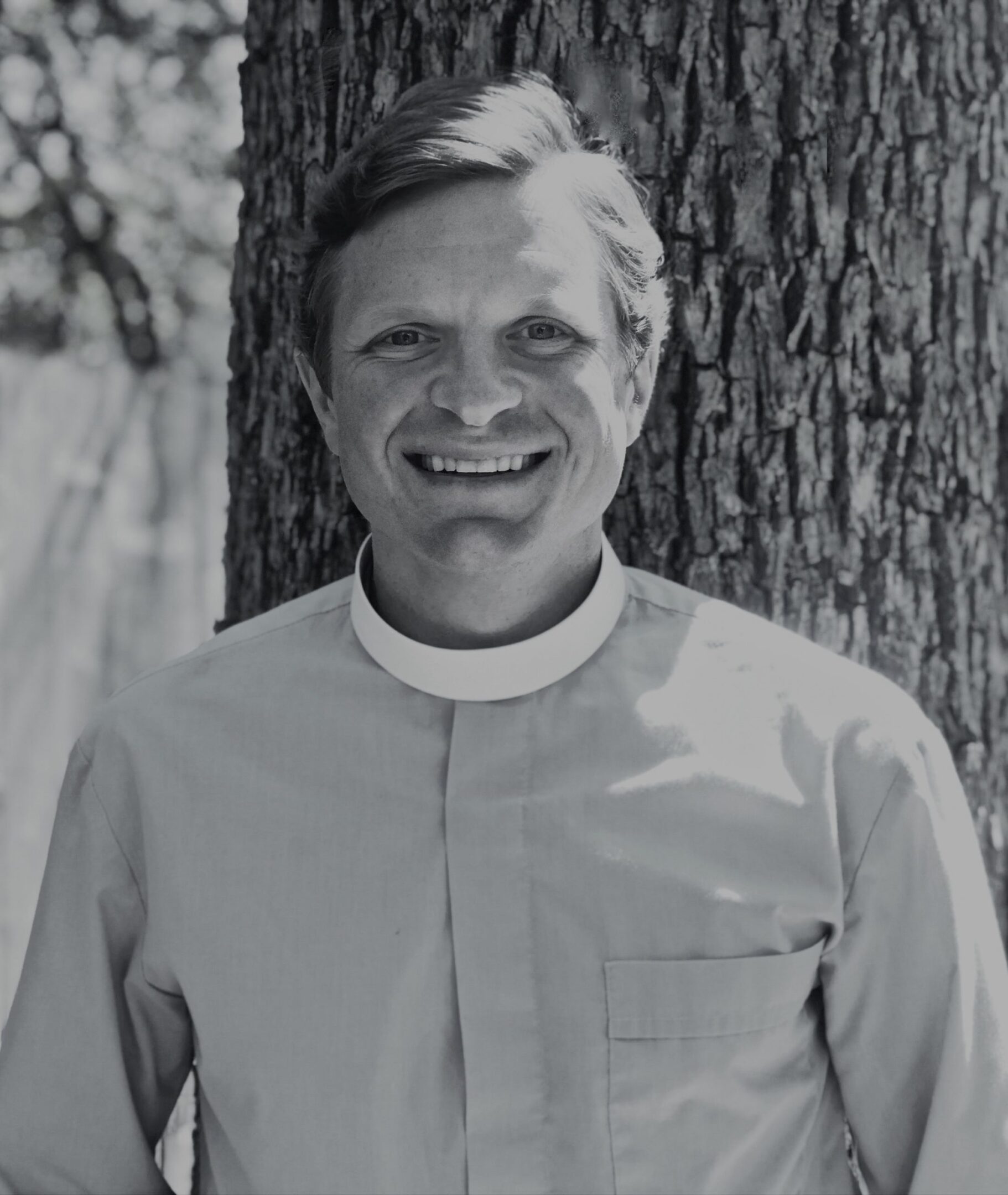Smiling person in clerical attire outdoors