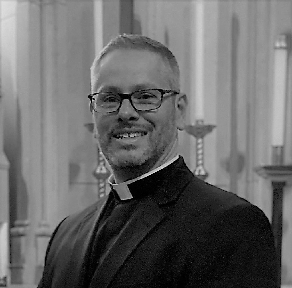 Smiling person with white collar and glasses
