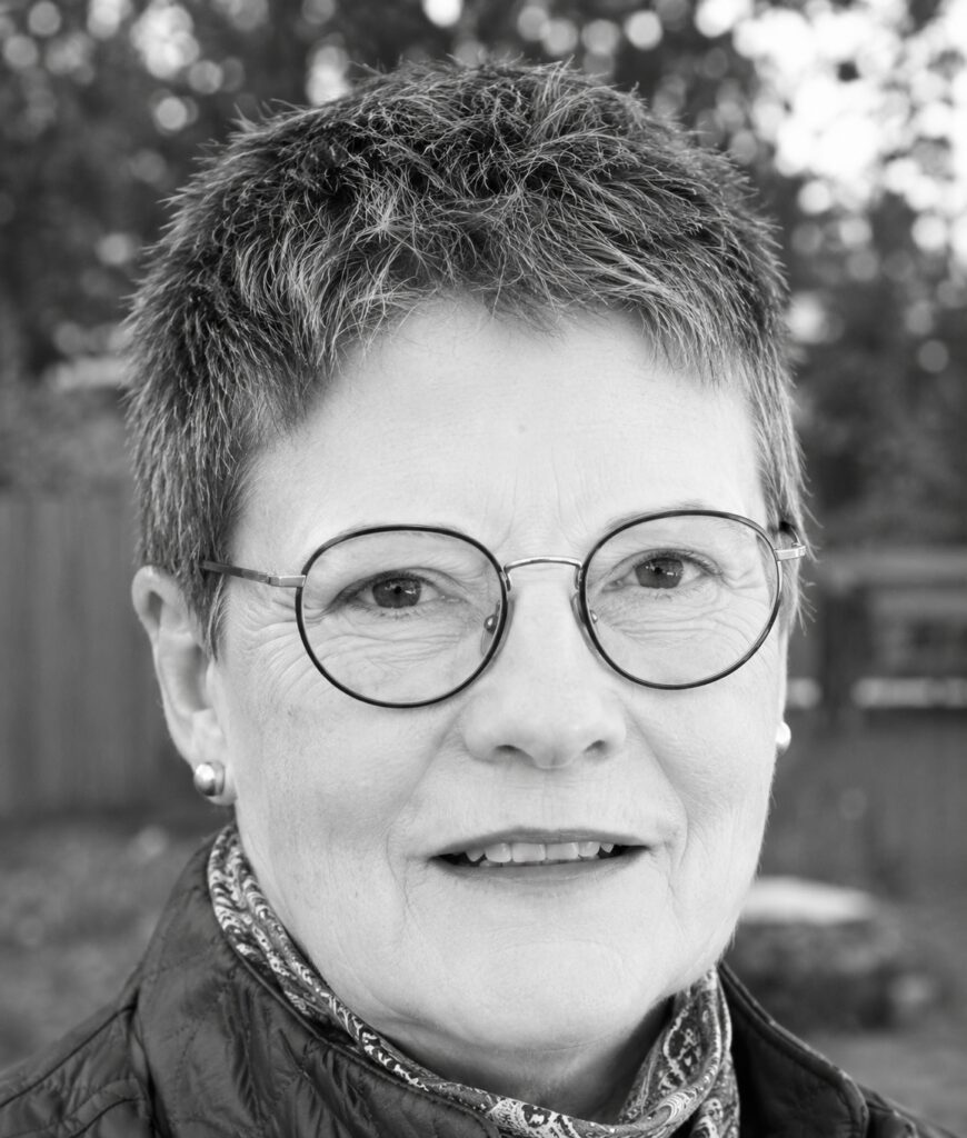 Older woman with short hair and round glasses