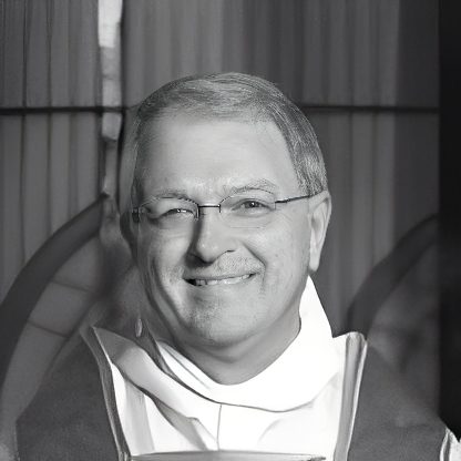 Smiling man wearing clerical collar and glasses