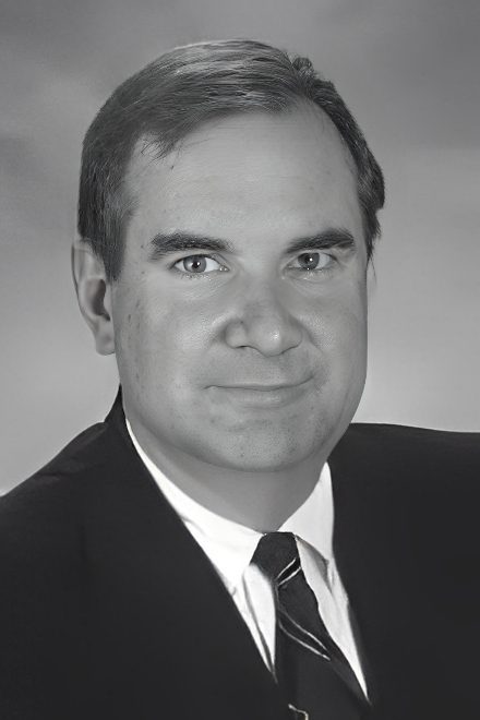 Formal headshot of man wearing suit and tie