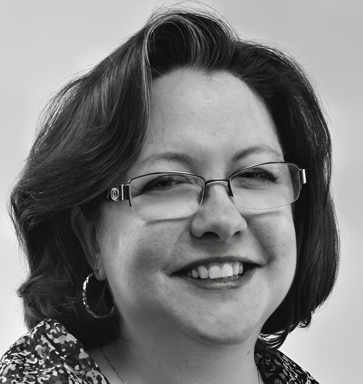 Smiling woman wearing glasses and hoop earrings