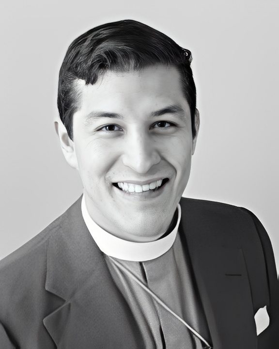 Black-and-white portrait of smiling man with clerical collar