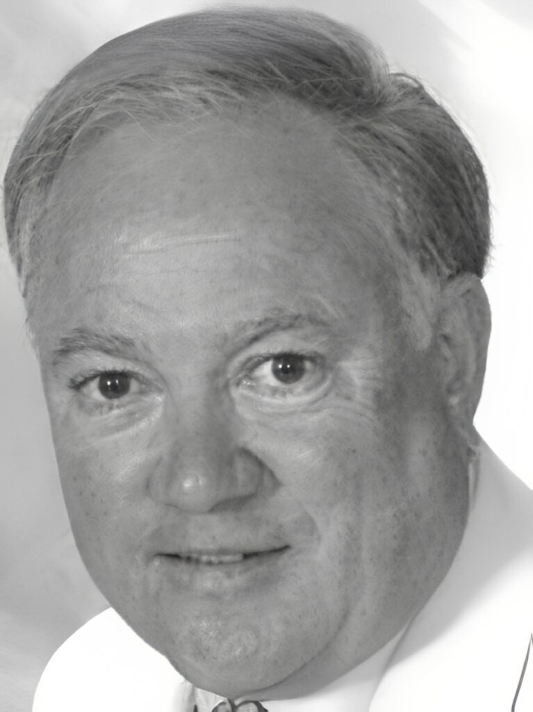Close-up grayscale headshot of smiling older man
