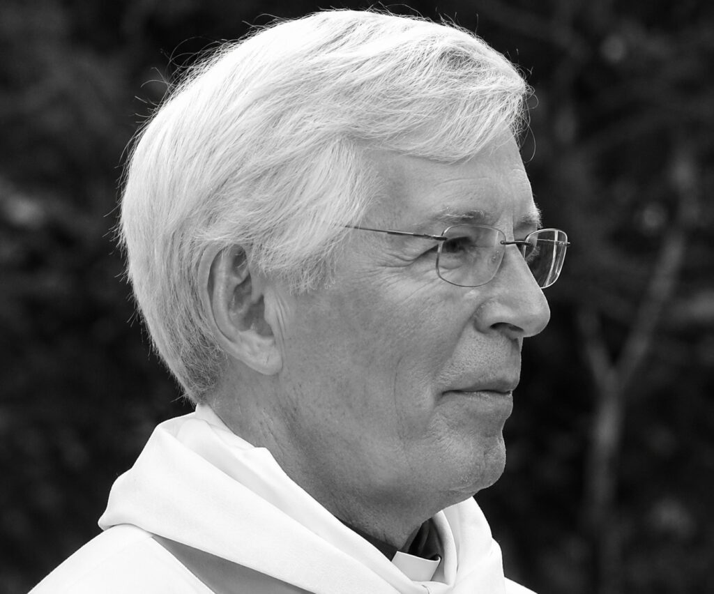 Elderly man wearing glasses in white robe